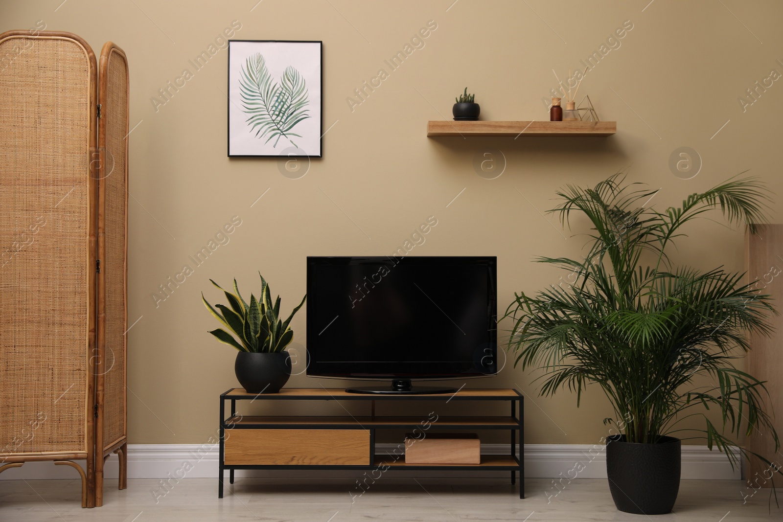 Photo of Modern TV on cabinet and green plants near beige wall in room. Interior design