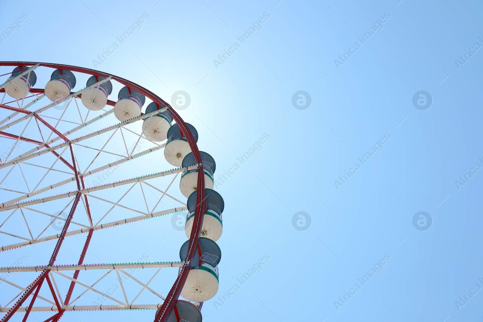 Photo of Beautiful Ferris wheel against blue sky on sunny day, low angle view