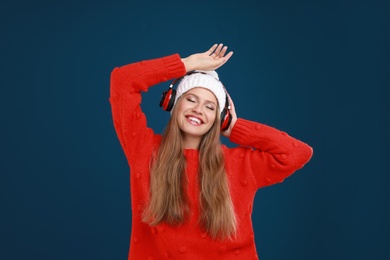 Photo of Young woman listening to music with headphones on dark blue background