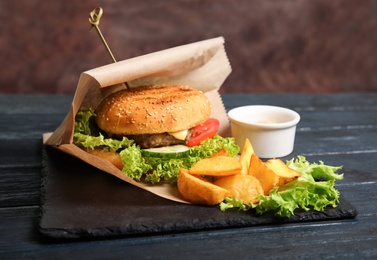 Photo of Tasty burger and fries served on slate plate