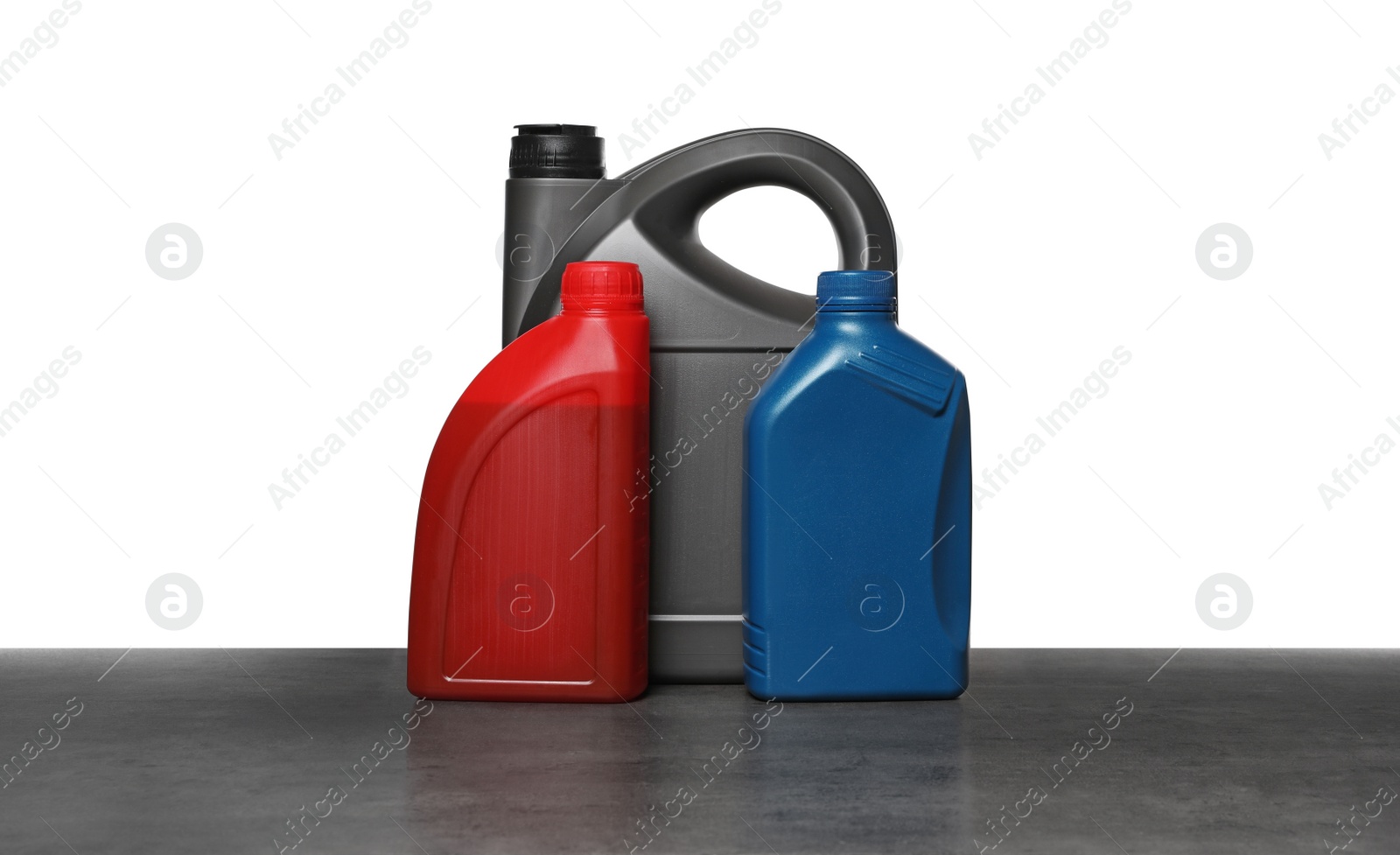 Photo of Motor oil in different containers on grey table against white background