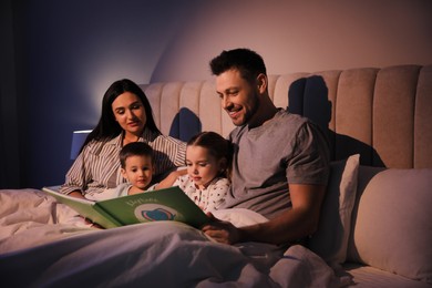 Photo of Family reading book together in bed at home