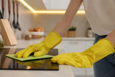 Photo of Woman with spray bottle and microfiber cloth cleaning electric stove in kitchen, closeup