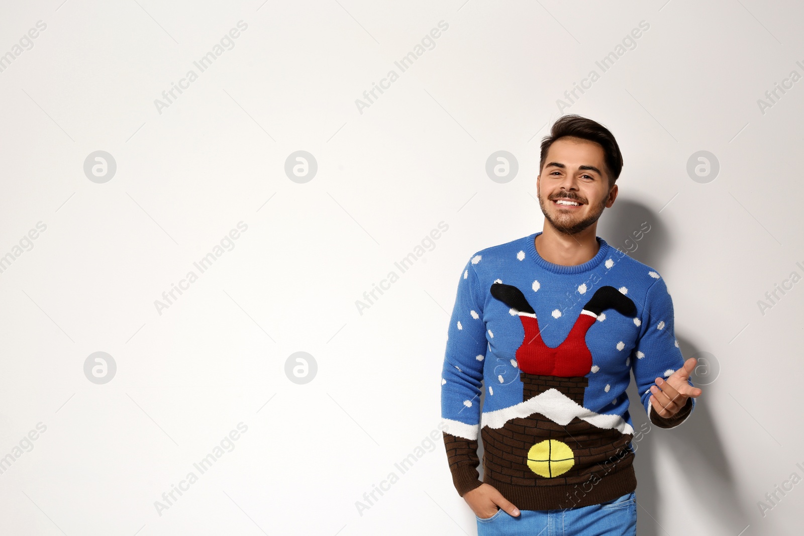 Photo of Young man in Christmas sweater on white background. Space for text