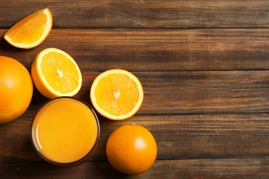 Photo of Glass of orange juice and fresh fruits on wooden background