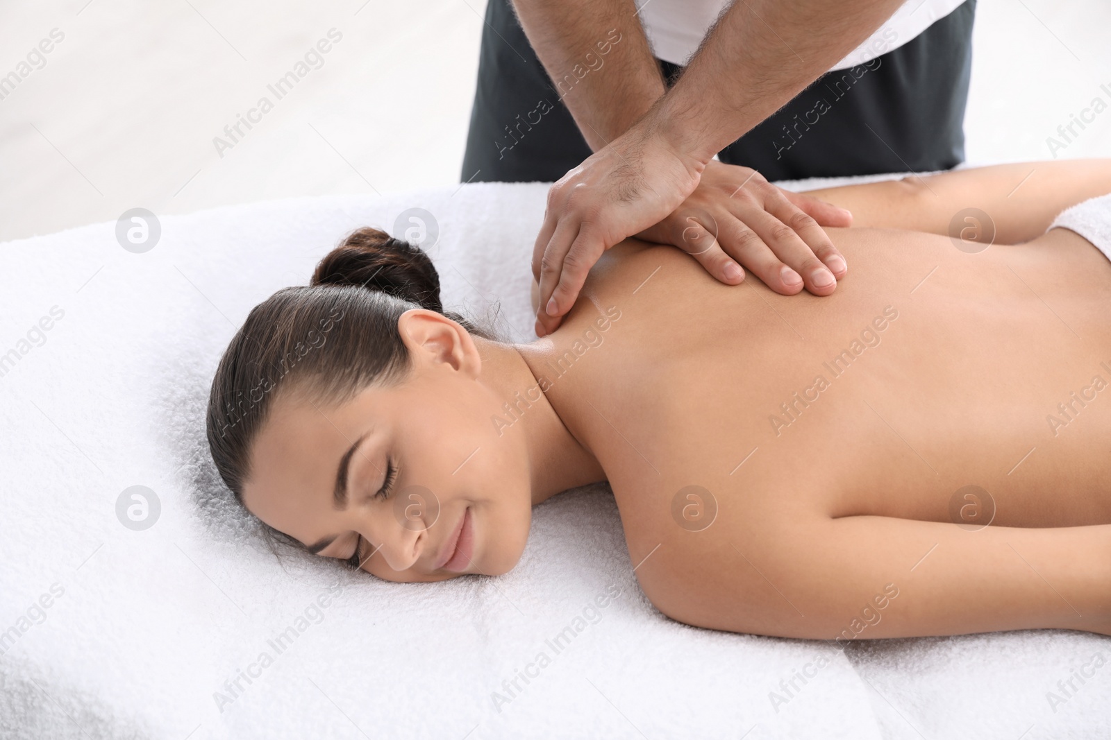 Photo of Relaxed woman receiving back massage in wellness center