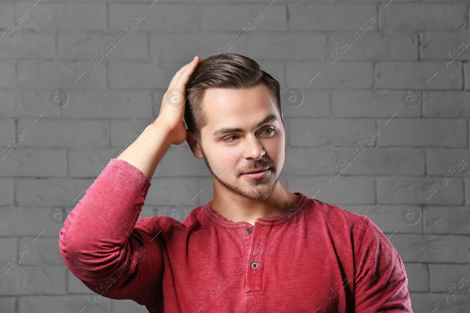 Photo of Portrait of young man with beautiful hair on brick wall background