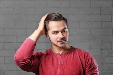 Portrait of young man with beautiful hair on brick wall background