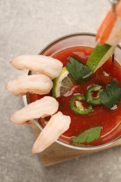 Tasty shrimp cocktail with sauce, parsley and lime in glass on light grey table, top view