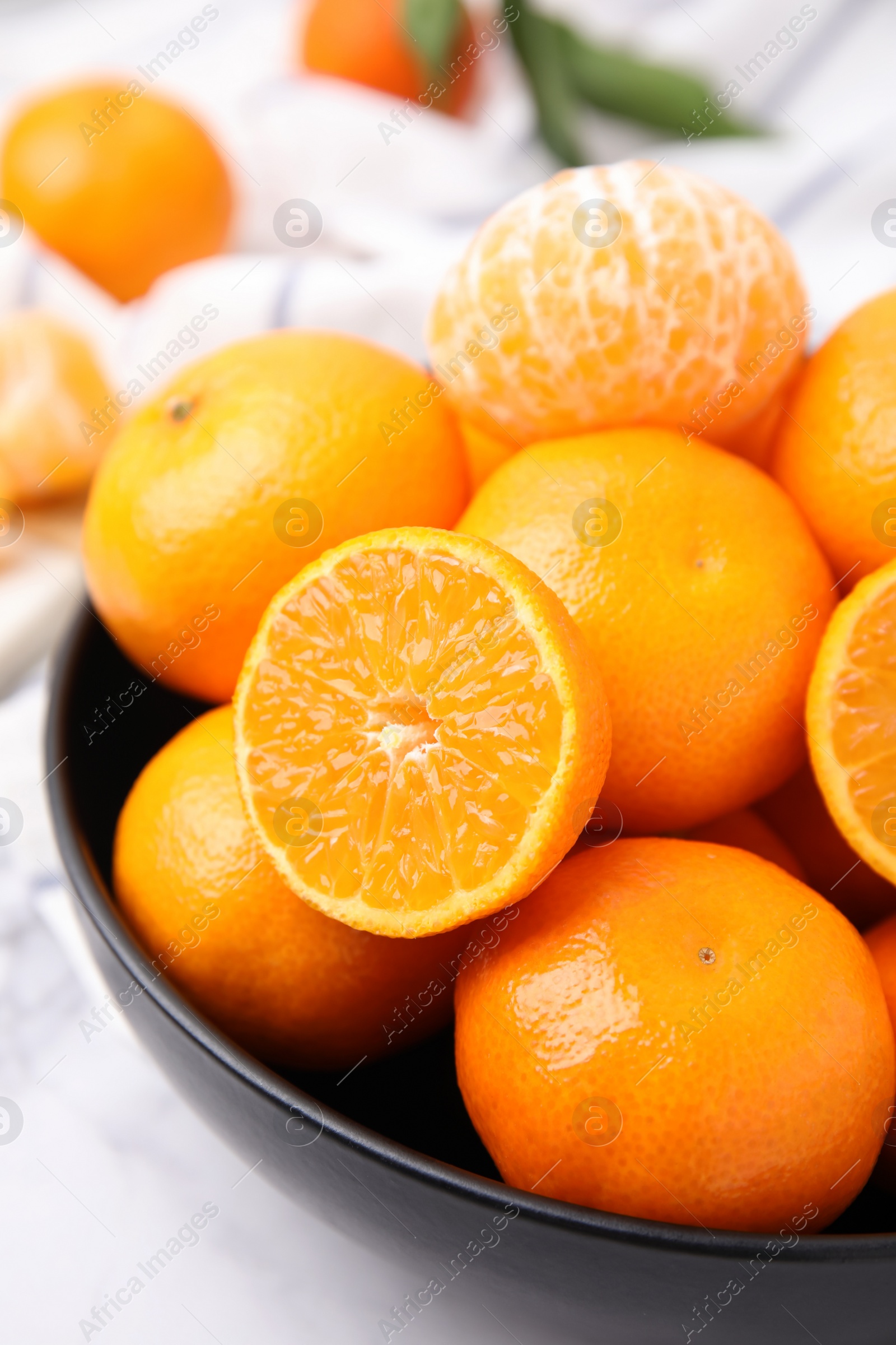 Photo of Bowl of fresh juicy tangerines on white table, closeup