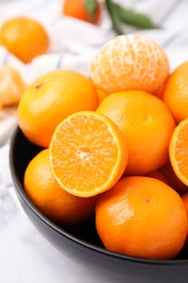 Photo of Bowl of fresh juicy tangerines on white table, closeup