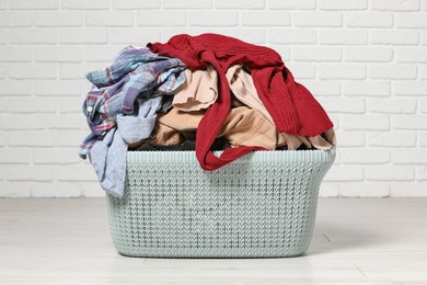 Photo of Laundry basket with clothes near white brick wall