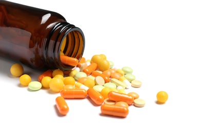 Bottle with vitamin pills and capsules on white background, closeup