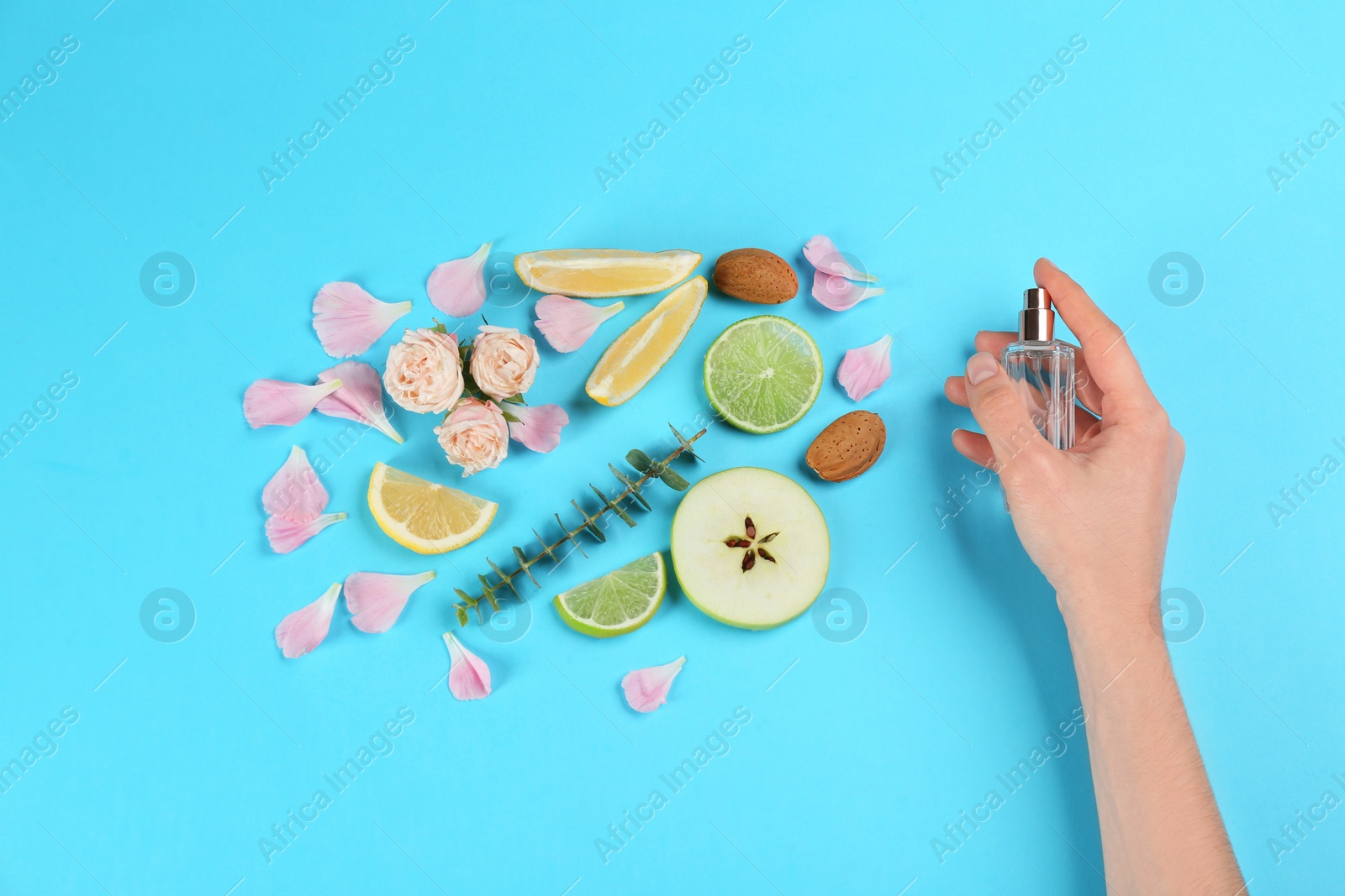 Photo of Woman with perfume. Fragrance composition, flowers and fruits on light blue background,  top view