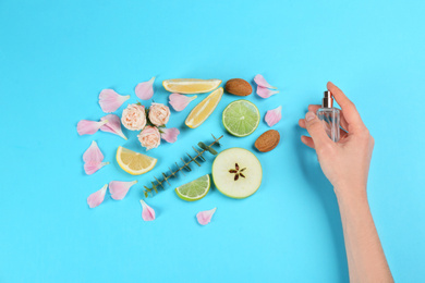 Photo of Woman with perfume. Fragrance composition, flowers and fruits on light blue background,  top view