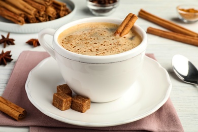 Photo of Delicious hot coffee with cinnamon and brown sugar on white table