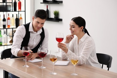 Sommeliers tasting different sorts of wine at table indoors