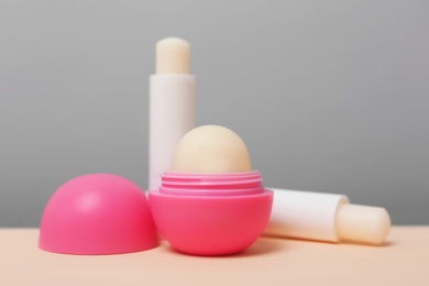 Photo of Hygienic lipsticks and balms on table against grey background