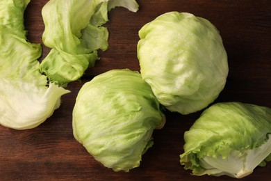 Fresh green iceberg lettuce heads and leaves on wooden table, flat lay