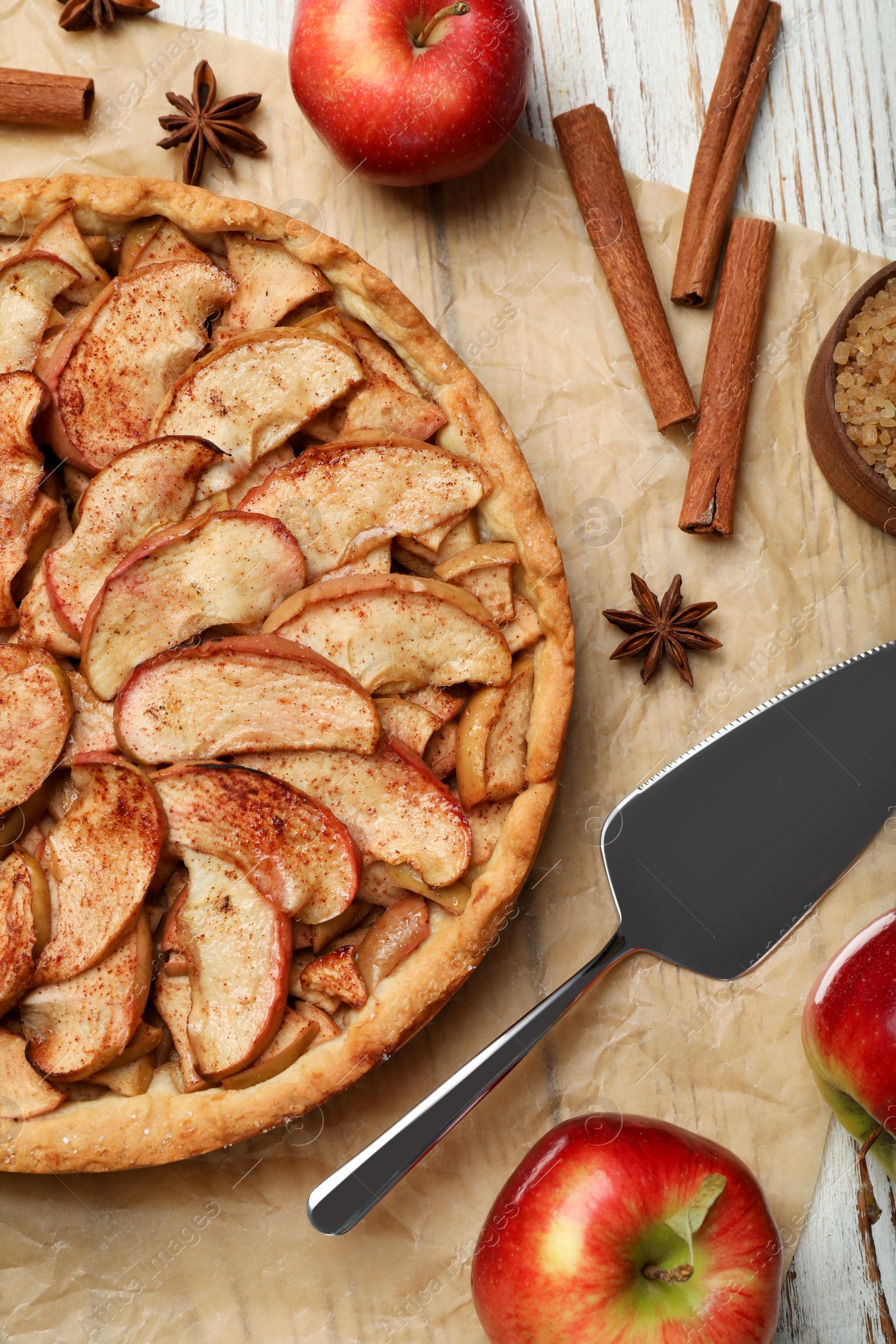 Photo of Delicious apple pie and ingredients on white wooden table, flat lay