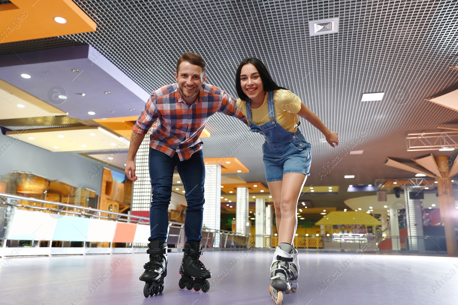 Photo of Young couple spending time at roller skating rink