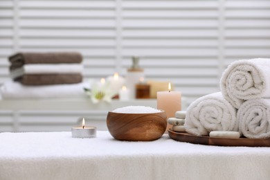 Photo of Spa composition with rolled towels and burning candles on massage table in wellness center, space for text