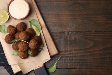 Photo of Delicious falafel balls served on wooden table, top view. Space for text