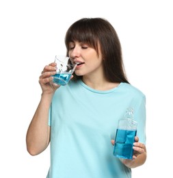 Young woman using mouthwash on white background