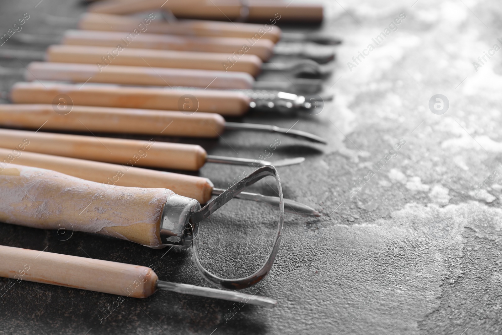 Photo of Set of different clay crafting tools on grey table, closeup. Space for text