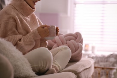 Photo of Woman with cup of drink relaxing at home, closeup. Cozy atmosphere