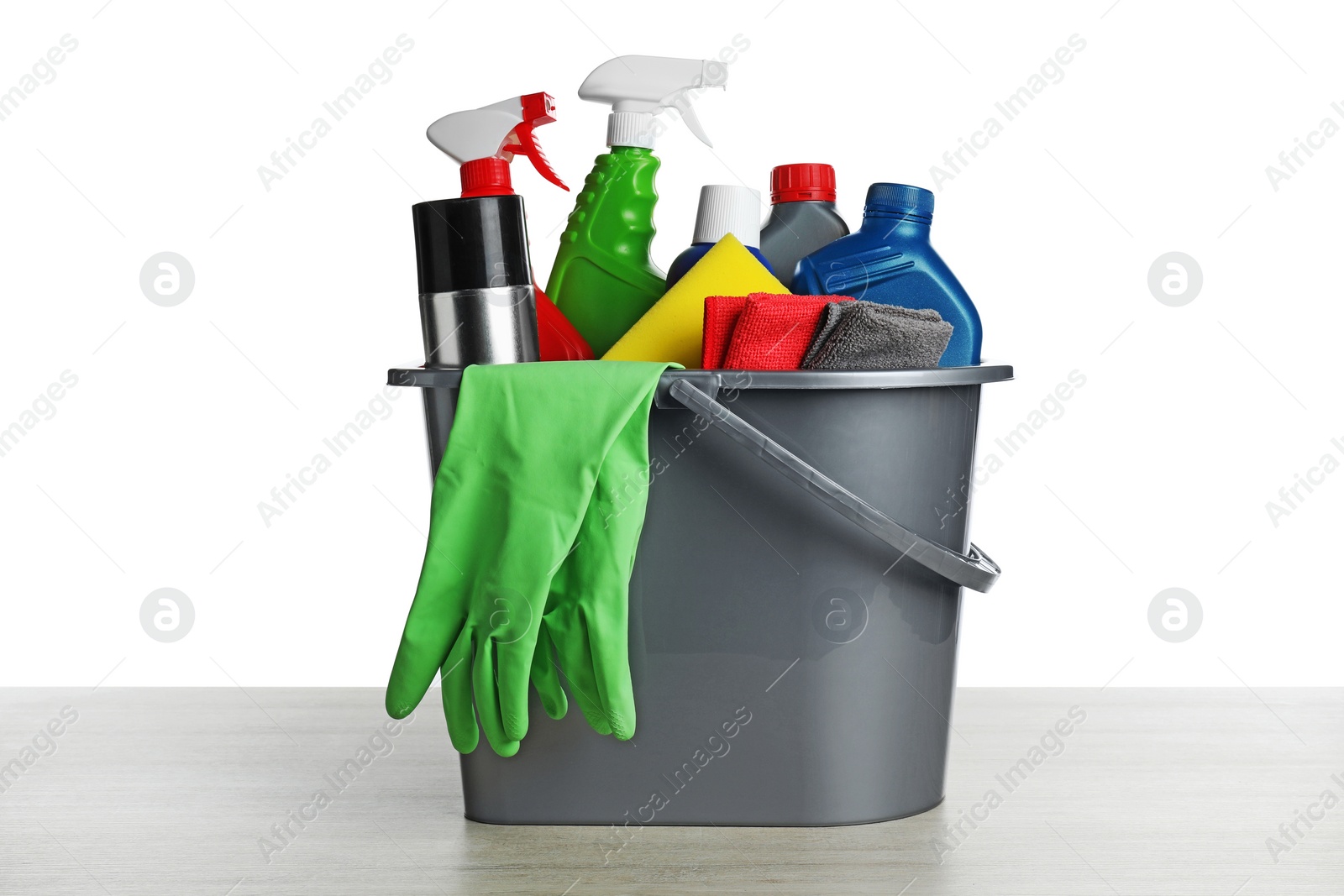 Photo of Grey bucket with car care products on wooden table against white background