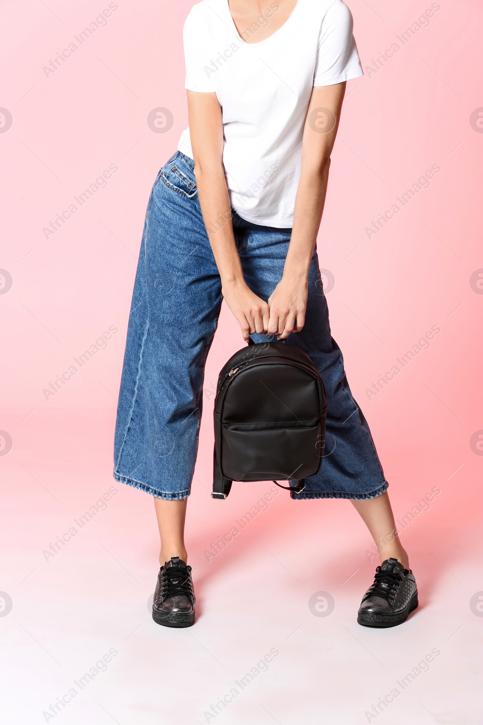 Photo of Fashionable woman in stylish shoes with backpack on color background