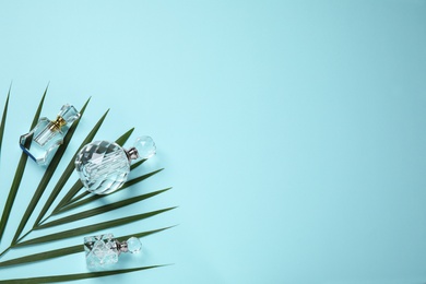 Photo of Flat lay composition with luxury perfumes and tropical leaf on light blue background. Space for text