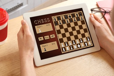 Image of Woman playing online chess on tablet indoors, closeup