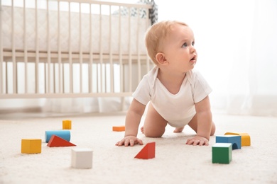 Photo of Cute little baby crawling on carpet indoors