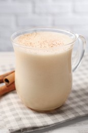 Photo of Delicious eggnog with cinnamon on wooden table, closeup