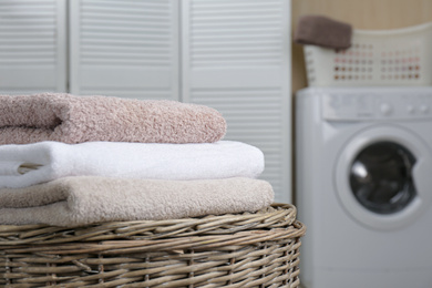 Photo of Fresh towels on wicker basket in laundry room. Space for text
