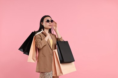 Photo of Beautiful woman with shopping bags on pink background. Space for text