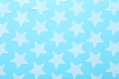 Photo of White star shaped confetti on light blue background, flat lay