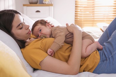 Photo of Happy young mother with her cute baby on bed at home