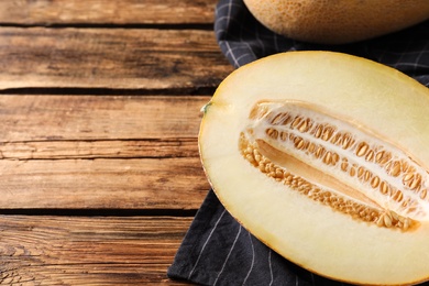 Photo of Delicious honey melon on wooden table, space for text
