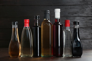 Photo of Bottles with different kinds of vinegar on wooden table