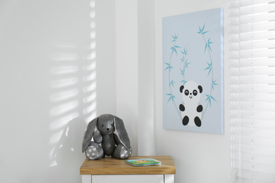 Photo of Child's room interior with chest of drawers, toy bunny and cute poster on wall