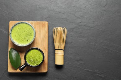 Photo of Cup of fresh matcha tea, bamboo whisk and green powder on black table, flat lay. Space for text