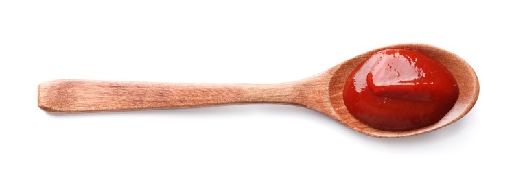 Photo of Tasty ketchup in wooden spoon isolated on white, top view