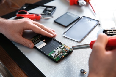 Photo of Technician repairing mobile phone at table, closeup