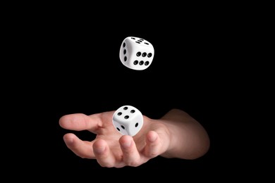 Image of Man throwing white dice on black background, closeup
