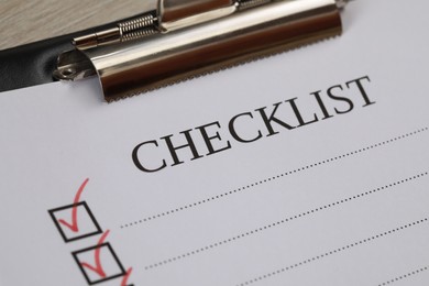 Photo of Clipboard with inscription Checklist on table, closeup