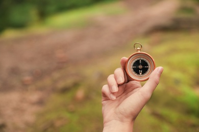 Photo of Woman checking modern compass in wilderness, closeup with space for text