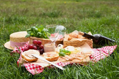 Photo of Picnic blanket with wine and food on green grass